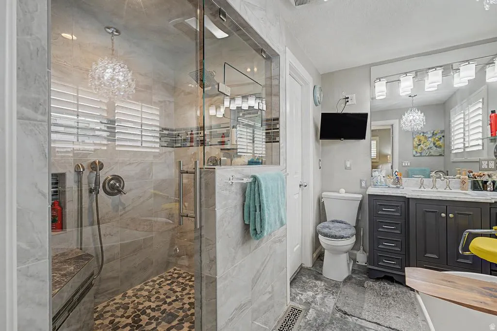 Glass-enclosed shower with a built-in bench, stone tile walls, and a pebble floor