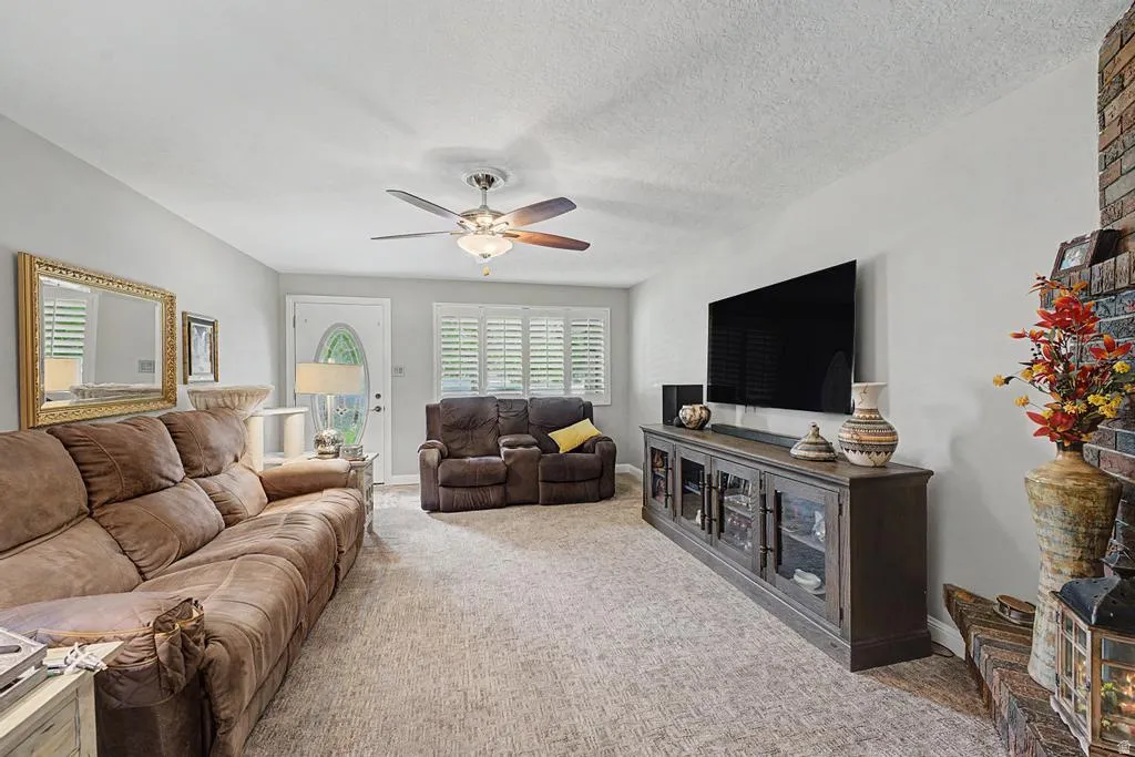 Textured carpeting, white walls, and a ceiling fan with integrated lighting