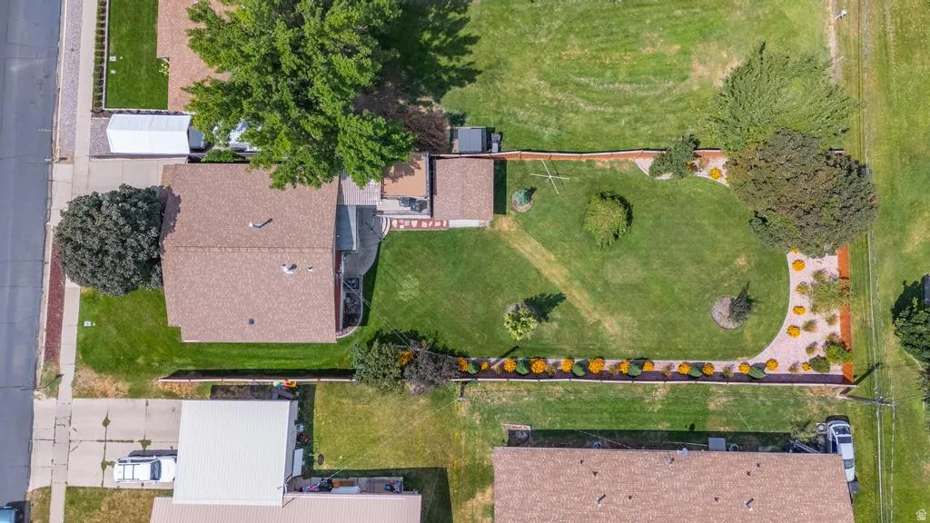 Pitched roof residence featuring a fenced backyard with a lawn, mature trees, and landscaping