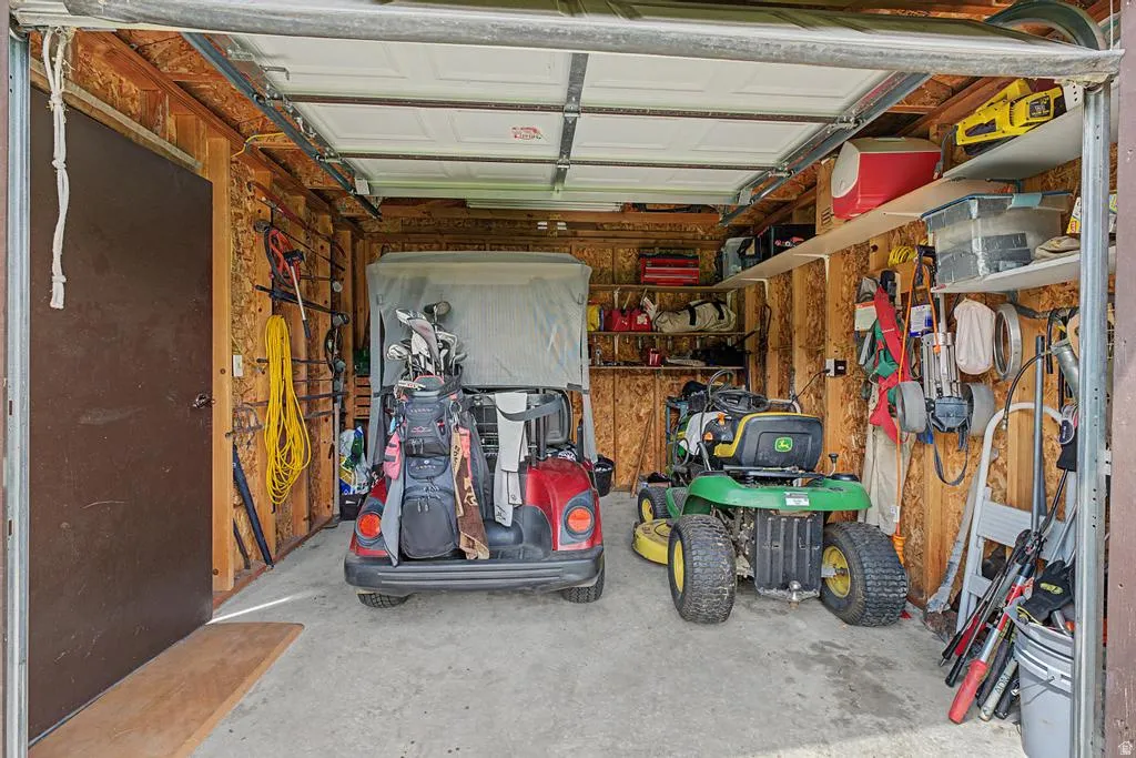 Single-car garage with a concrete floor, exposed wood-paneled walls, and built-in shelving