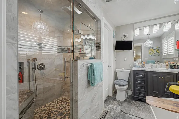 Glass-enclosed shower with a built-in bench, stone tile walls, and a pebble floor