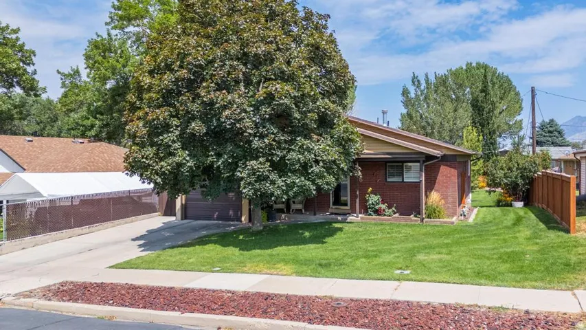 Brick exterior with a peaked roofline, attached garage, and a concrete driveway