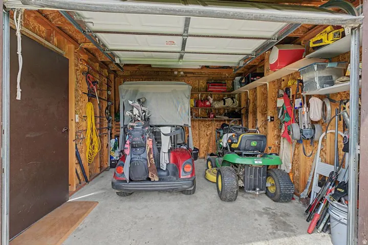 Single-car garage with a concrete floor, exposed wood-paneled walls, and built-in shelving