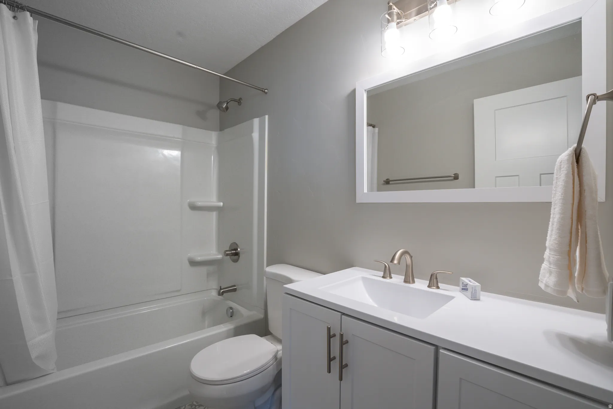 White vanity with brushed nickel hardware, integrated sink, and wall-mounted mirror