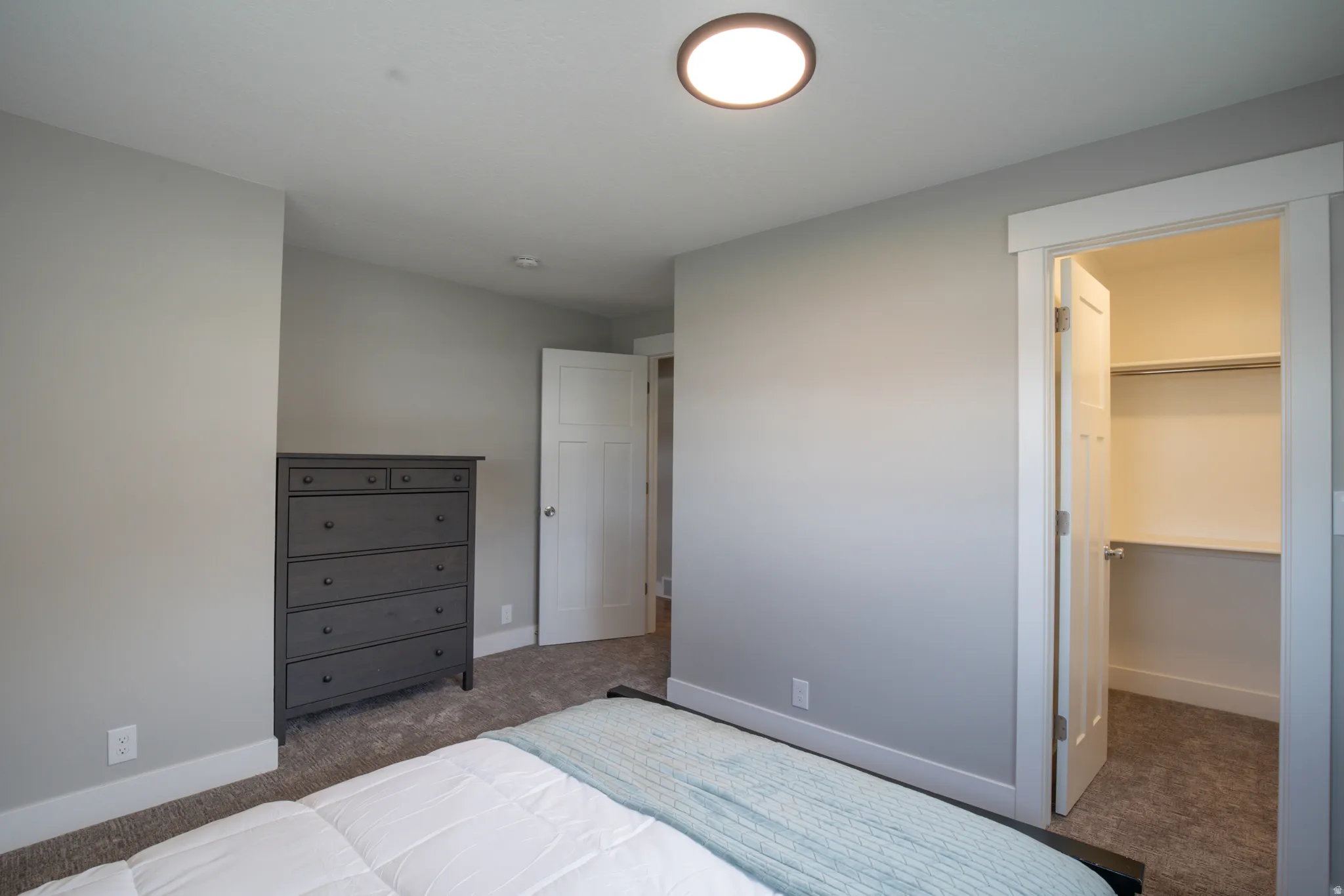 Primary Bedroom featuring neutral wall finishes, recessed ceiling lighting, a dark wood dresser, and direct access to a walk-in closet with shelving