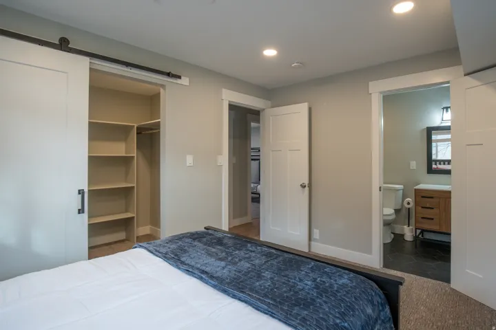 Recessed lighting, barn door closet with built-in shelving, wood-finish vanity with square sink, matte black vanity light, and dark-finish flooring