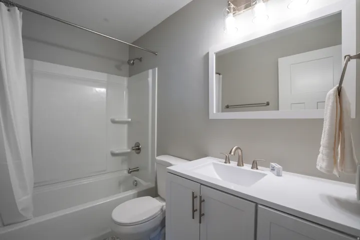 White vanity with brushed nickel hardware, integrated sink, and wall-mounted mirror