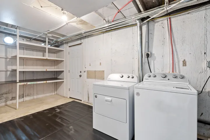 Laundry area with built-in shelving, white washer, and white dryer