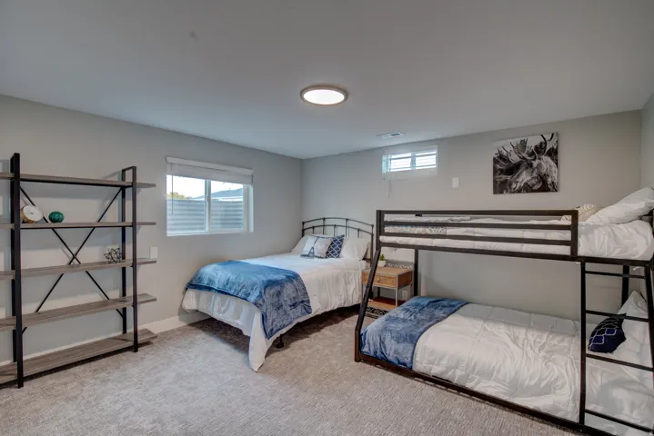 Recessed lighting, light gray wall paint, window with blinds, gray textured carpeting, built-in shelving unit