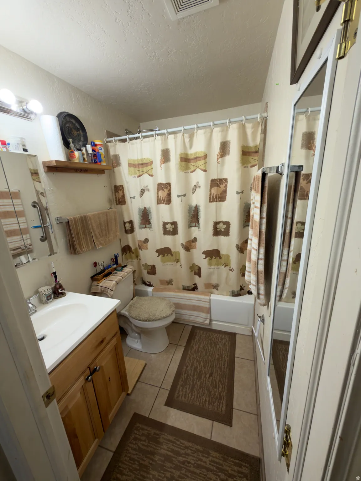 Bathroom featuring a wood-finish vanity with an integrated sink, a built-in bathtub, and tile flooring