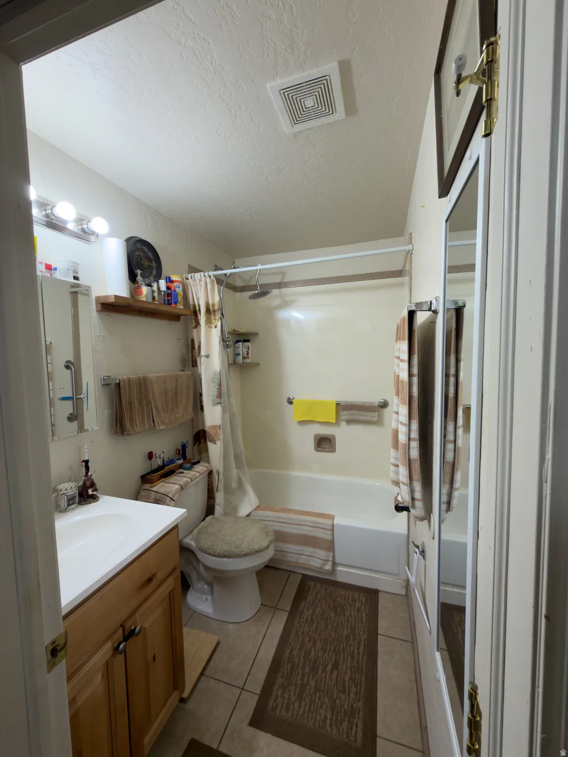 Bathroom featuring a wood-finish vanity with a white countertop, a white toilet, and a bathtub with a shower combination