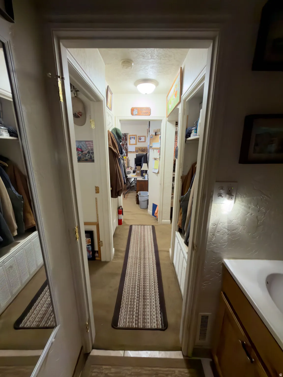 Carpeted hallway with built-in storage benches and overhead lighting