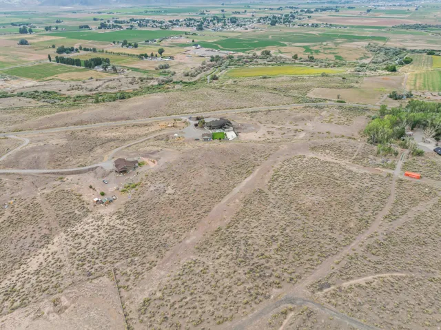 Expansive rural landscape featuring multiple structures, natural terrain, and distant cultivated fields