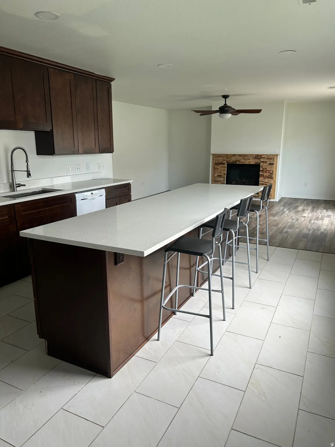 Kitchen with dark wood cabinetry, light-toned countertops, and a white tile floor