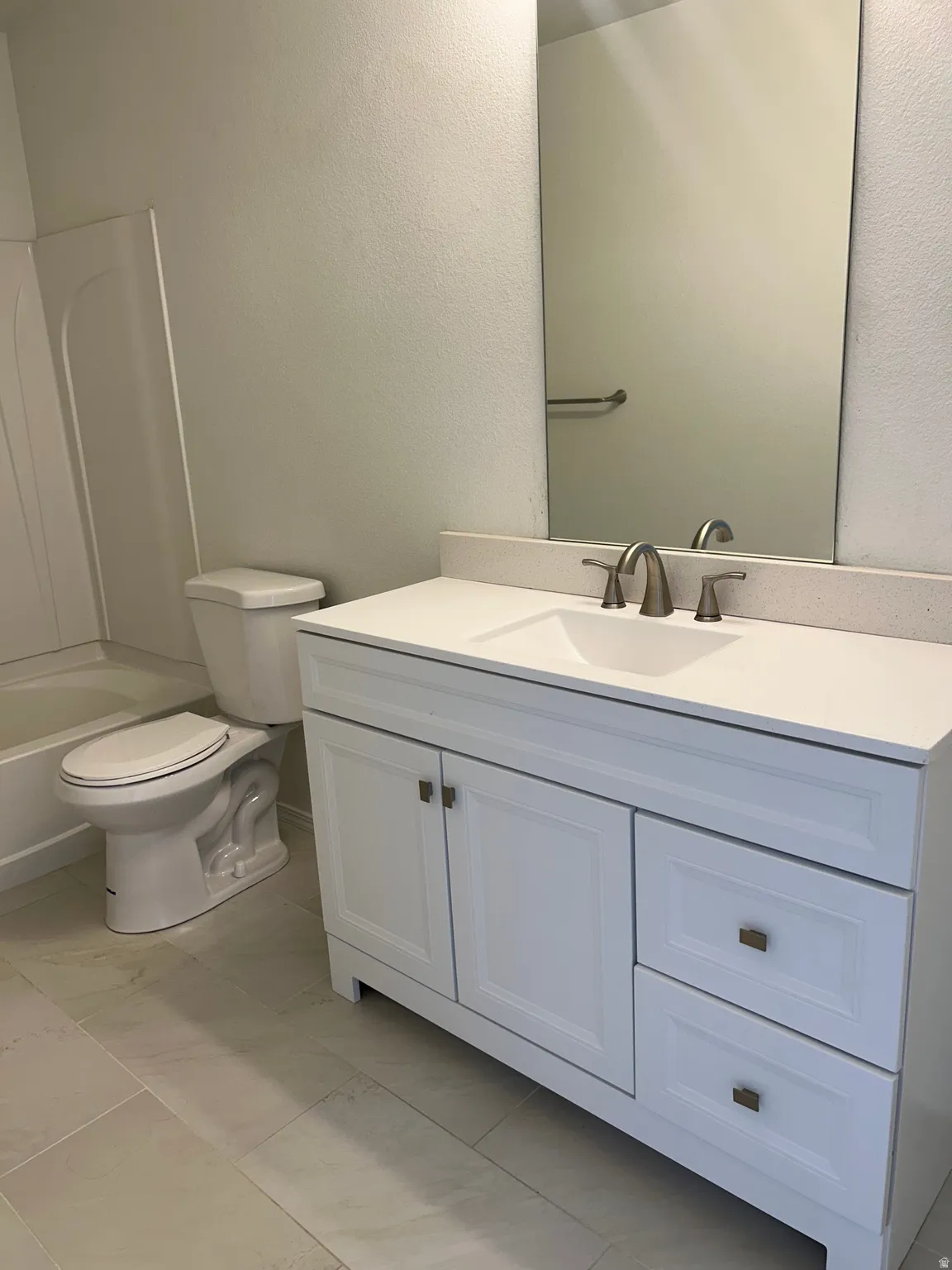 White vanity with shaker-style door and drawer fronts, single-basin sink, and brushed nickel hardware