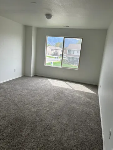 Spacious room featuring neutral wall paint, gray carpet, and a window with mountain scenery