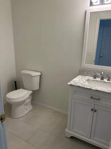 White vanity with a stone countertop, undermount sink, and chrome fixtures