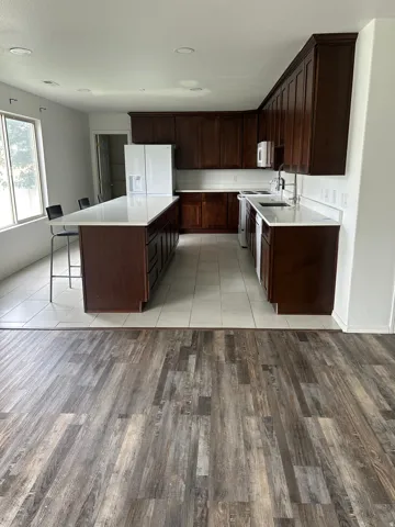 Modern kitchen featuring dark wood cabinetry, white quartz countertops, stainless steel appliances, and a large center island with seating