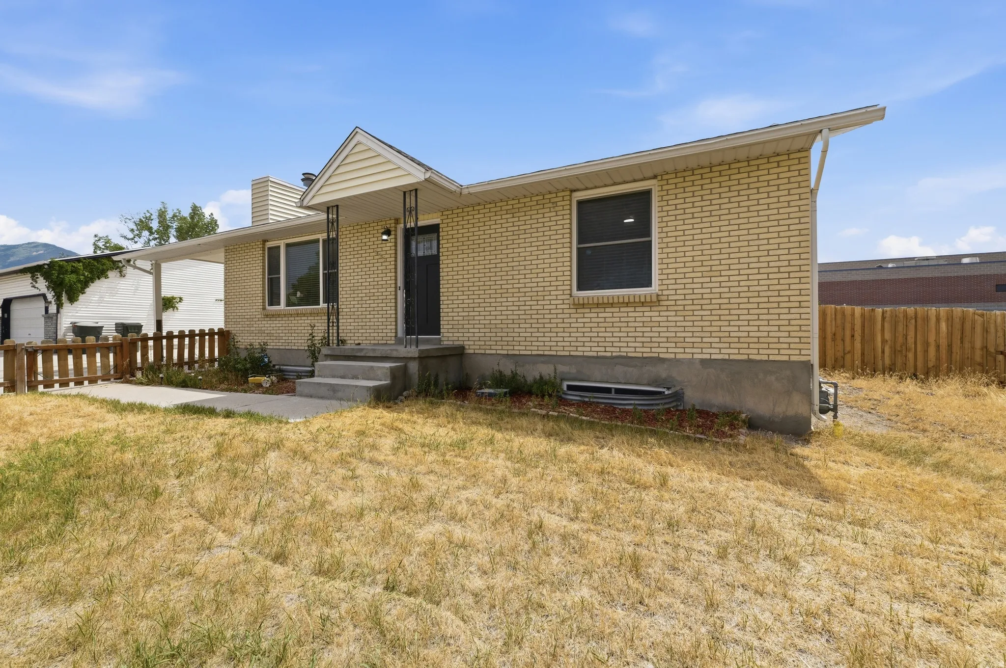 Brick exterior, covered entry, concrete steps, concrete walkway, and fenced area