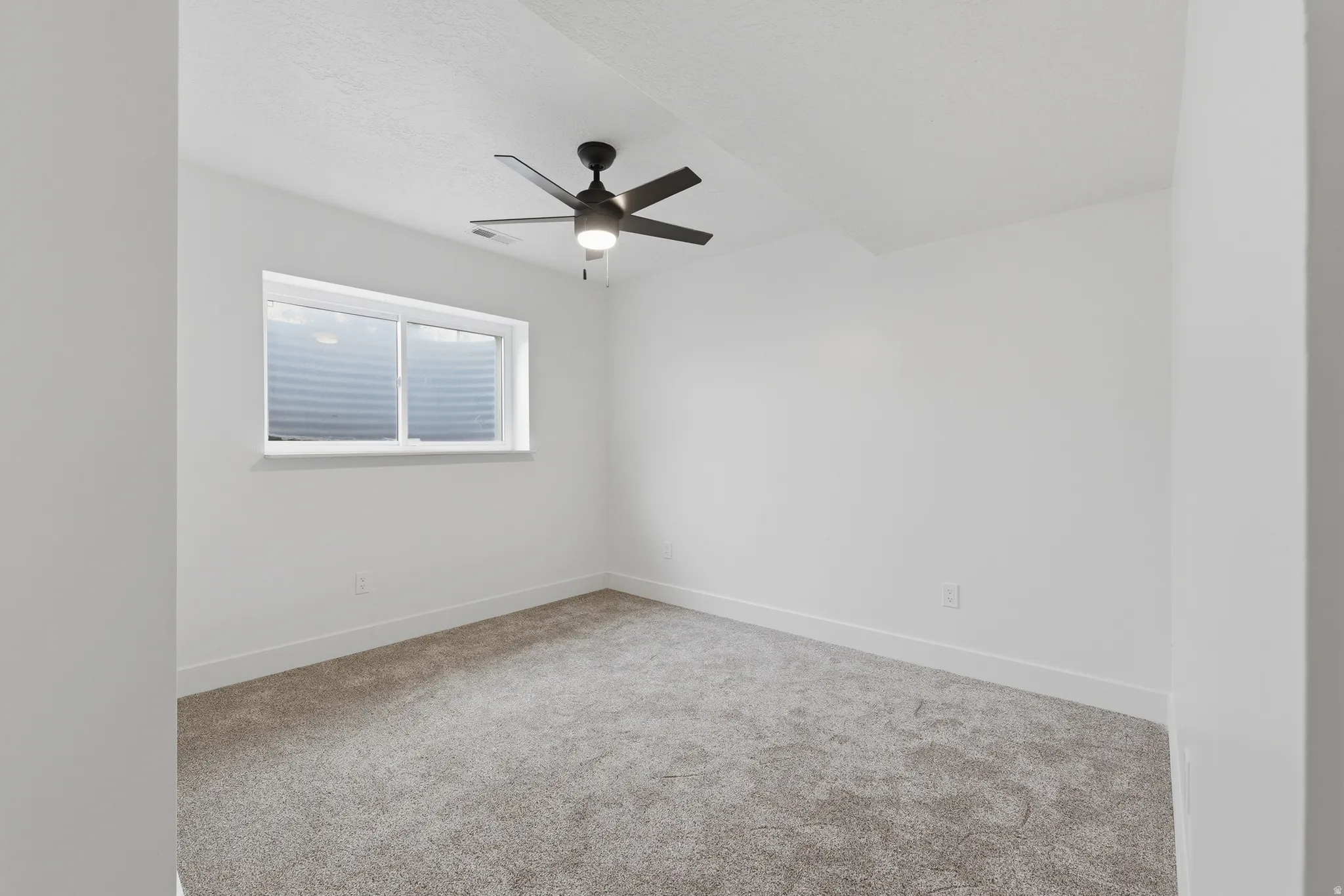 Recessed window with white trim, gray carpet, and a ceiling fan with integrated lighting