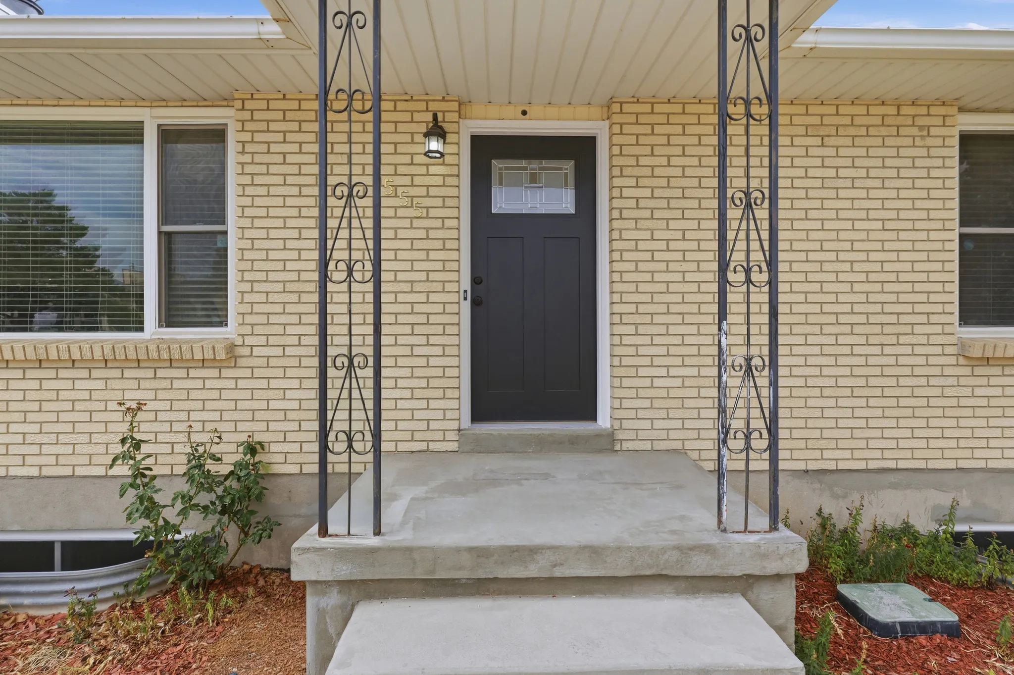 Cream brick exterior with white trim windows and a dark entry door