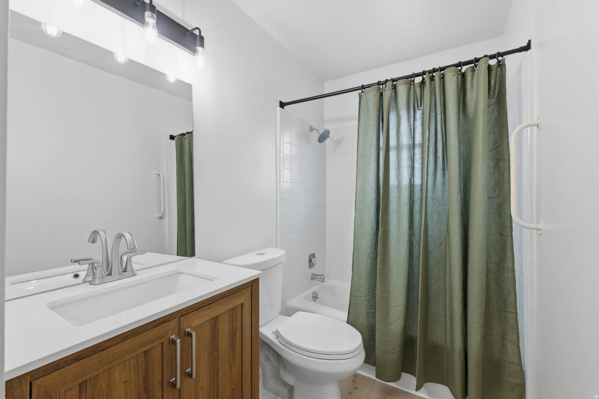 Wood-finish vanity with white countertop, undermount sink, and brushed nickel fixtures