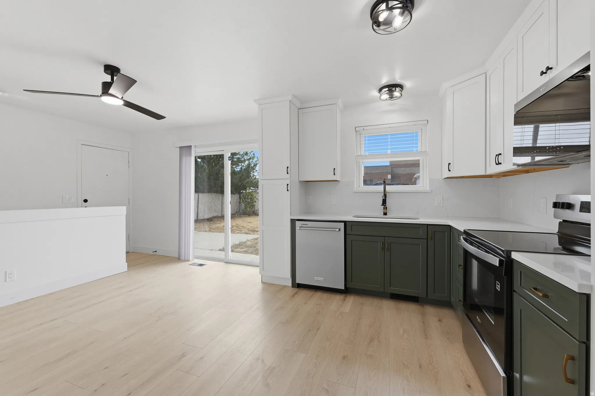 Kitchen featuring white upper cabinetry, dark lower cabinetry, light-toned wood-finish flooring, and a stainless steel appliance package