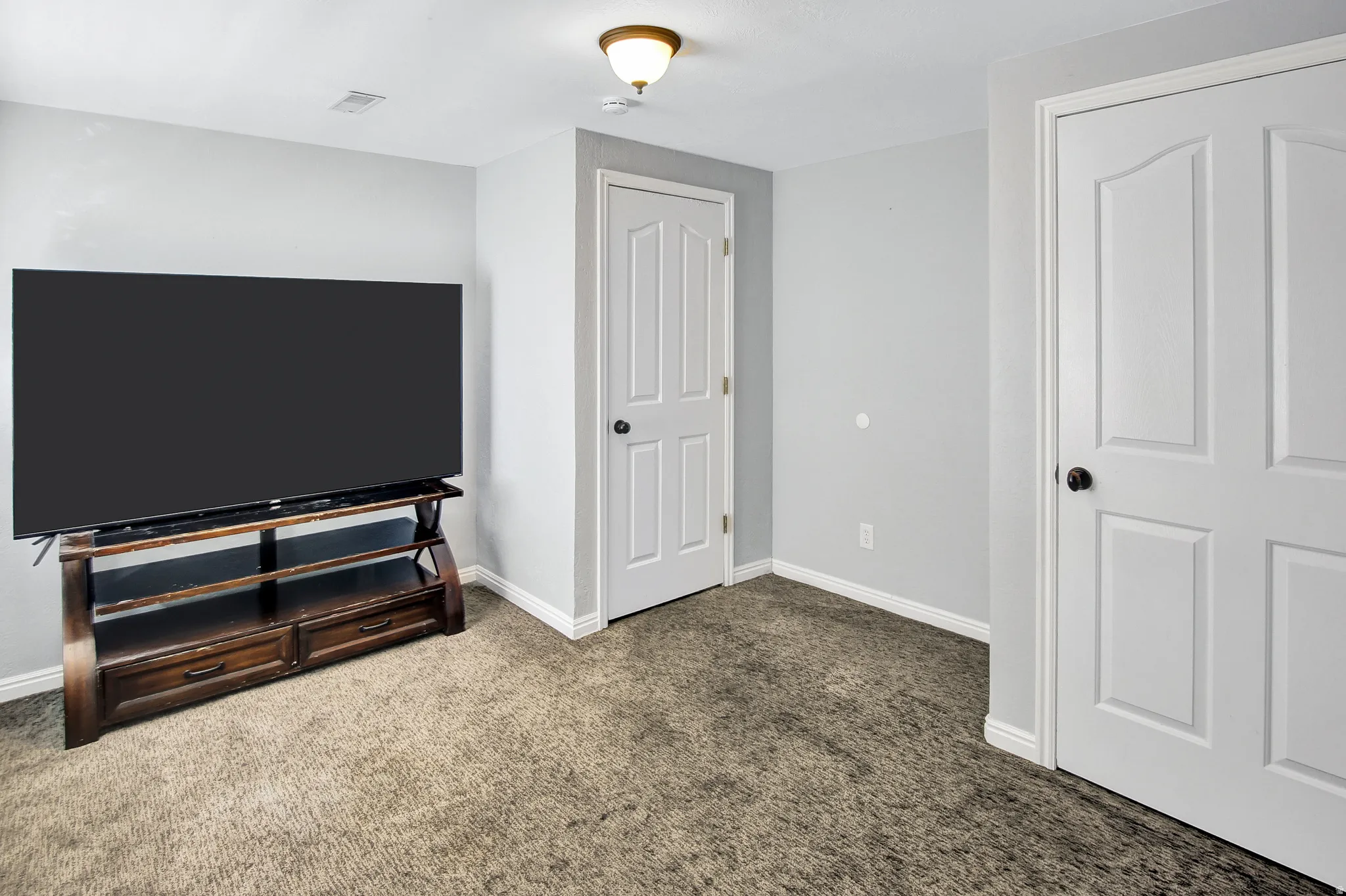 Wall-to-wall carpet flooring with light gray walls, white trim, and white paneled doors