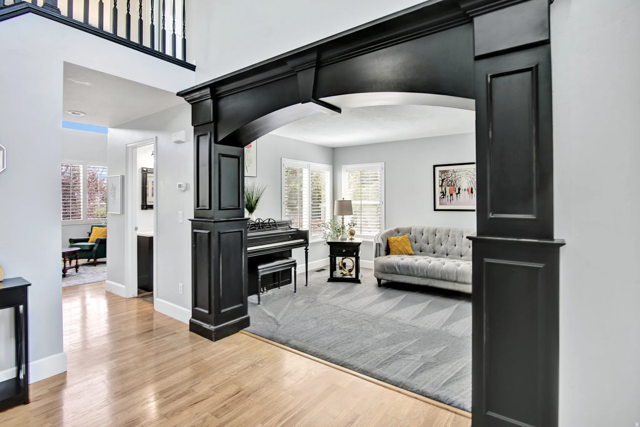 Arched entry featuring detailed dark trim, bright wood-finish flooring, and white wall finishes
