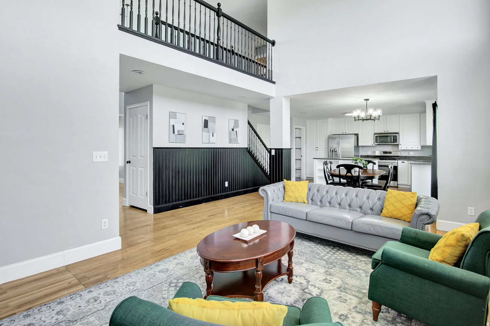 Open-concept living area with high ceilings, wood-finish flooring, and a two-story balcony overlooking the space