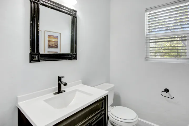Black framed mirror over a white vanity with an integrated sink and black faucet