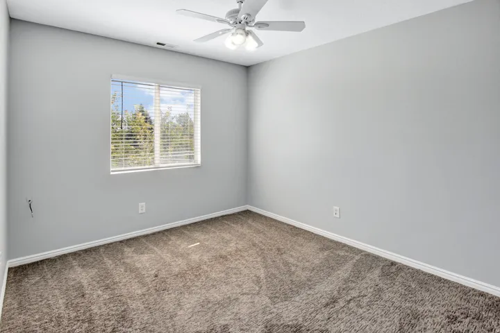 Neutral tone wall finishes, window with horizontal blinds, overhead ceiling fan, and carpeted flooring