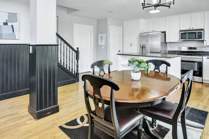 Open-concept kitchen with white cabinetry, stainless steel appliances, and a granite island