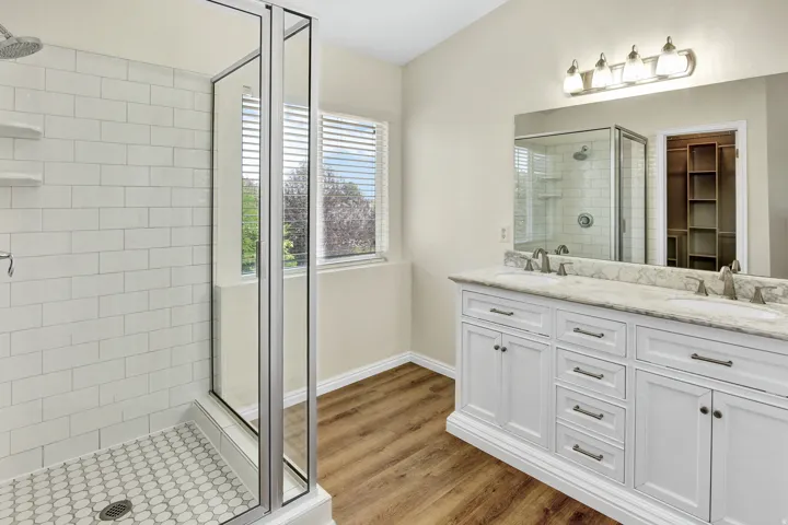 Glass-enclosed shower with white subway tile walls and penny tile flooring