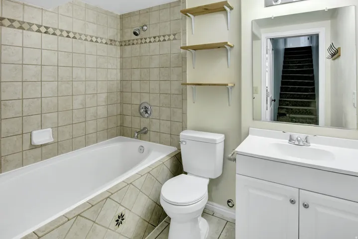 Bathtub with tiled surround, wall-mounted showerhead, and chrome fixtures