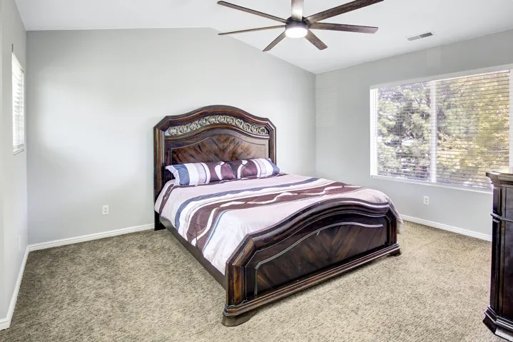 Vaulted ceiling with a ceiling fan, broad window with blinds, and carpeted flooring