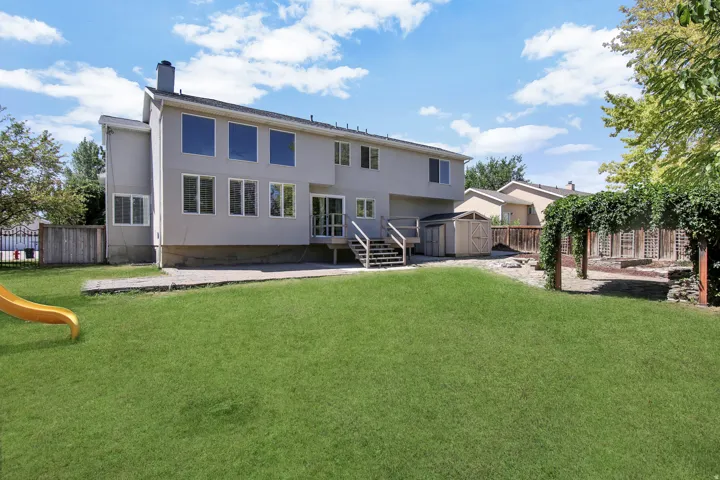 Expansive lawn area with a concrete patio, wood deck, and a detached shed
