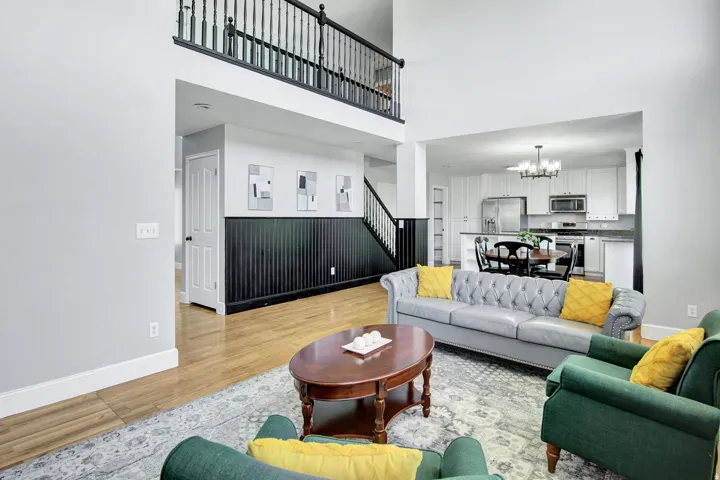 Open-concept living area with high ceilings, wood-finish flooring, and a two-story balcony overlooking the space