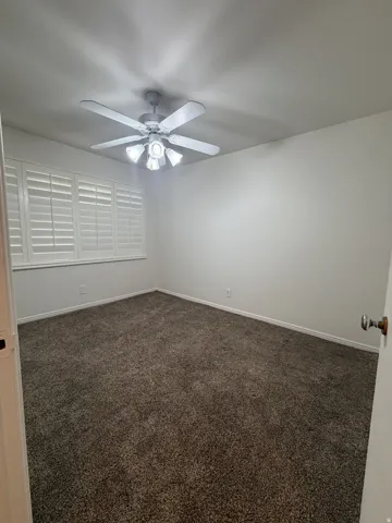 Wall-to-wall carpeting, ceiling fan with integrated lighting, and plantation shutters