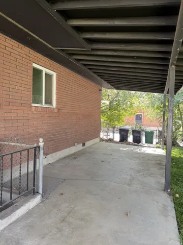 Covered concrete patio with brick exterior and white window