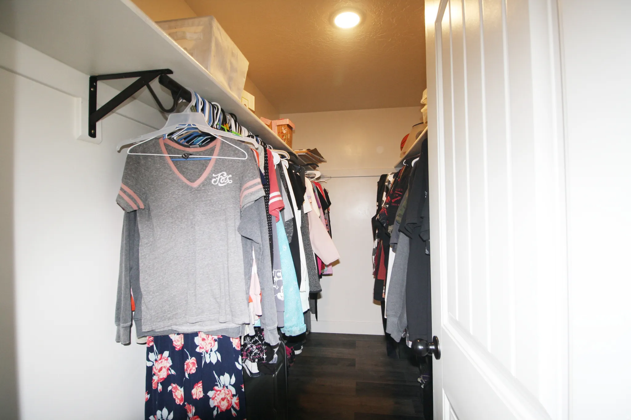 Walk-in closet with dark wood-finish flooring, white shelving, and a recessed ceiling light