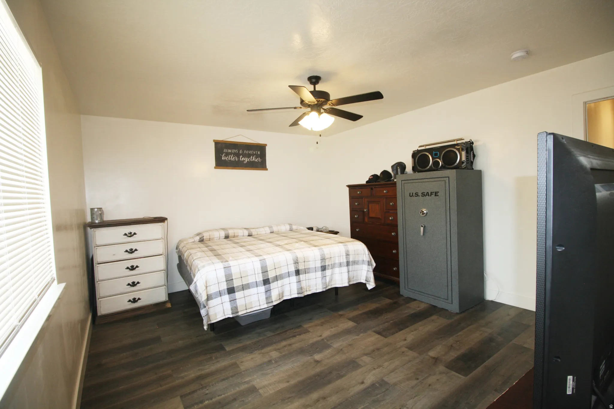 Wood-finish flooring with white walls and a ceiling fan