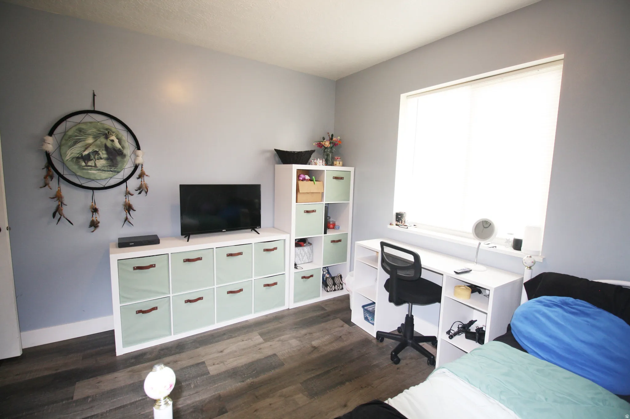 Wood-finish flooring, light grey wall paint, and a built-in desk with integrated shelving