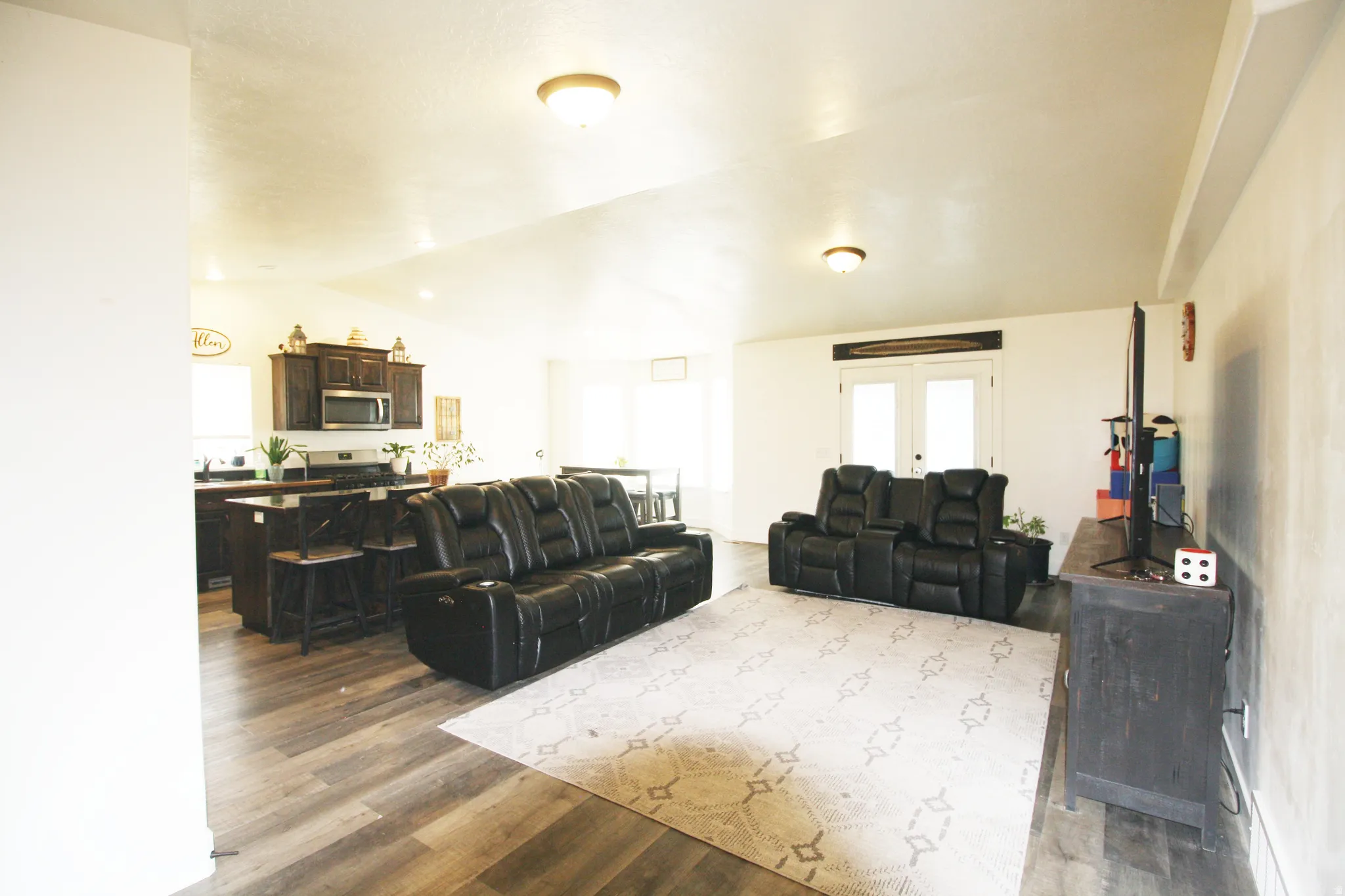 Open-concept living area with vaulted ceilings, wood-finish flooring, and recessed lighting