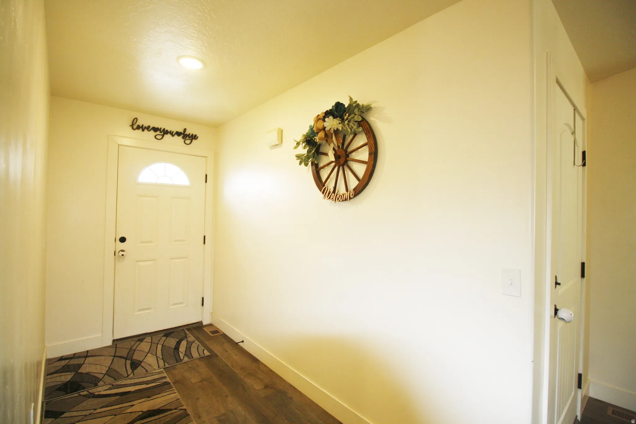 Entryway featuring a white paneled door with an arched glass insert, recessed ceiling lighting, and wood-finish flooring