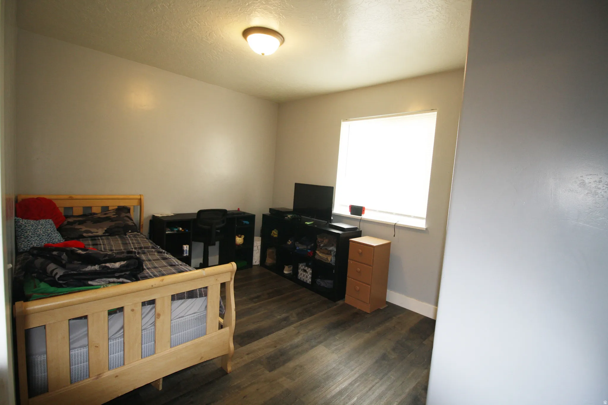 Wood-finish flooring, single window with blinds, ceiling-mounted light fixture
