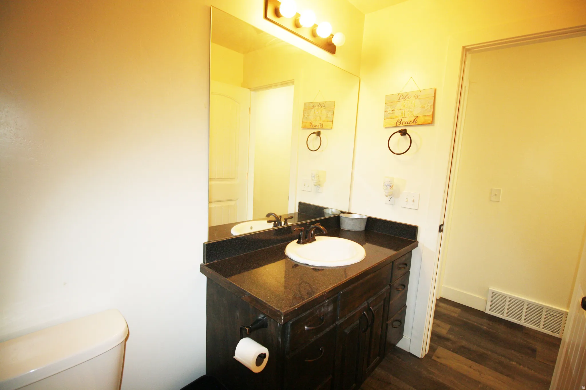 Dark wood-finish vanity with a single basin sink, bronze-finish faucet, and a large wall-mounted mirror