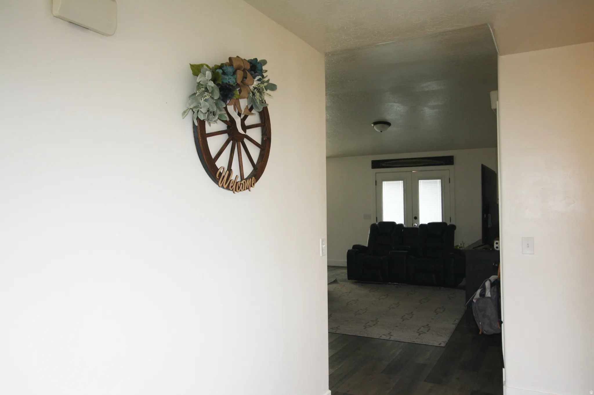Wood-finish flooring leading to a living area with dual French doors and an overhead light fixture