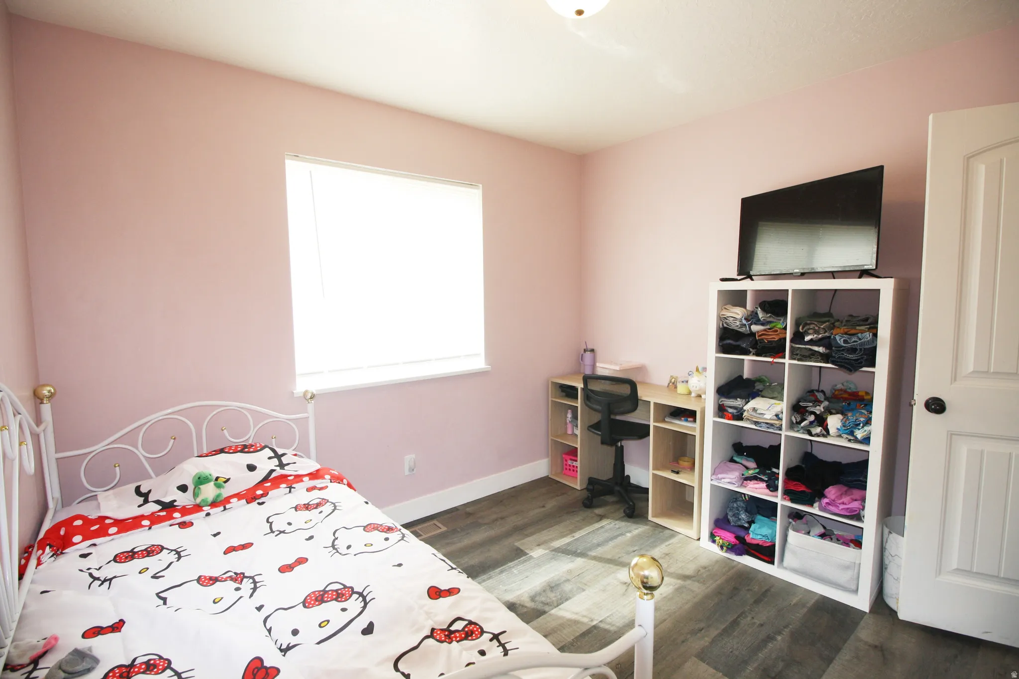 Neutral wall color, wood-finish flooring, and a single window with blinds