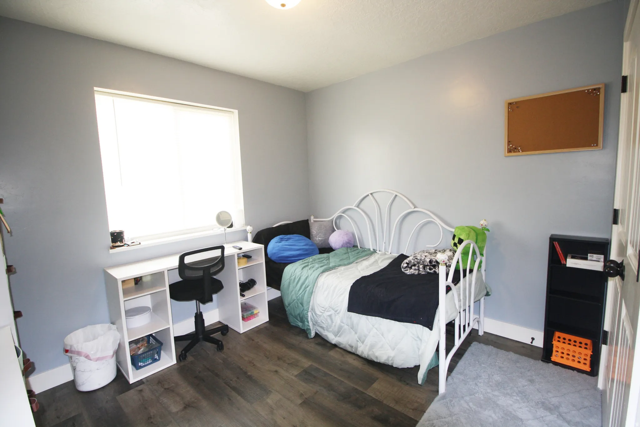 Window with a white frame, wood-finish flooring, and light blue wall color